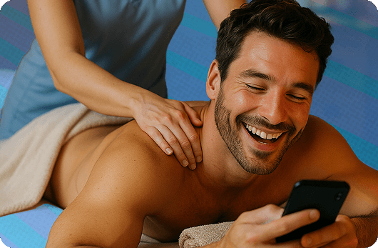 A man looking at his phone while receiving a massage